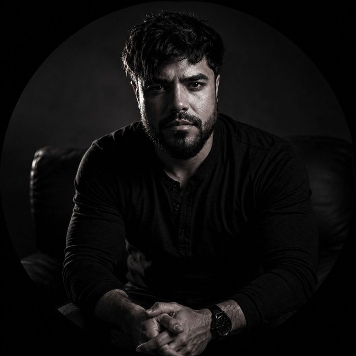 Retrato de Marcos Silveira em preto e branco, sentado, com as mãos cruzadas
